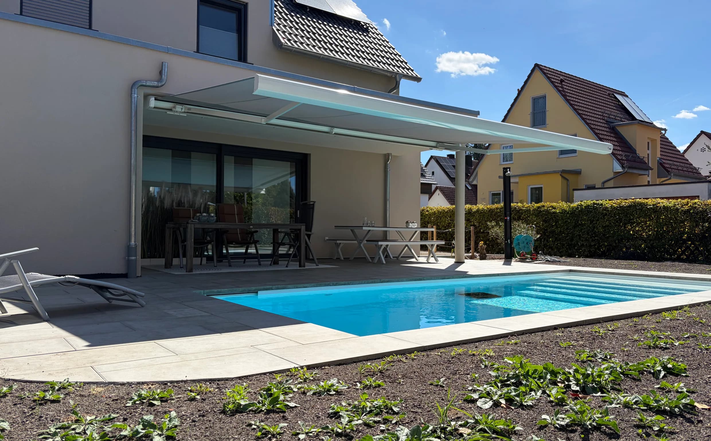 Weiße Gelenkarmmarkise über Terrasse und Pool, eingebaut von raumdecor schnell